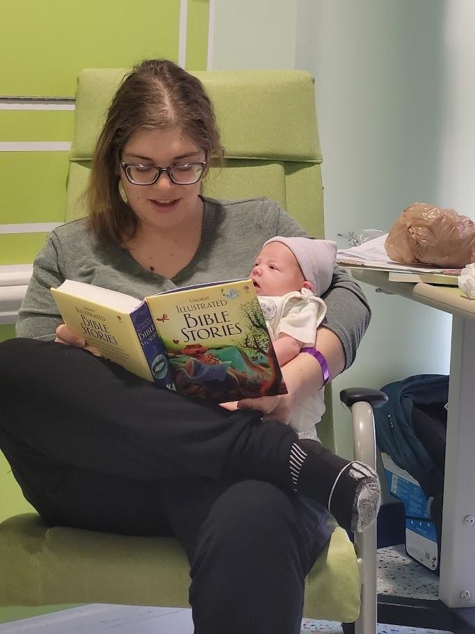 A woman reading an illustrated Bible stories book to a baby